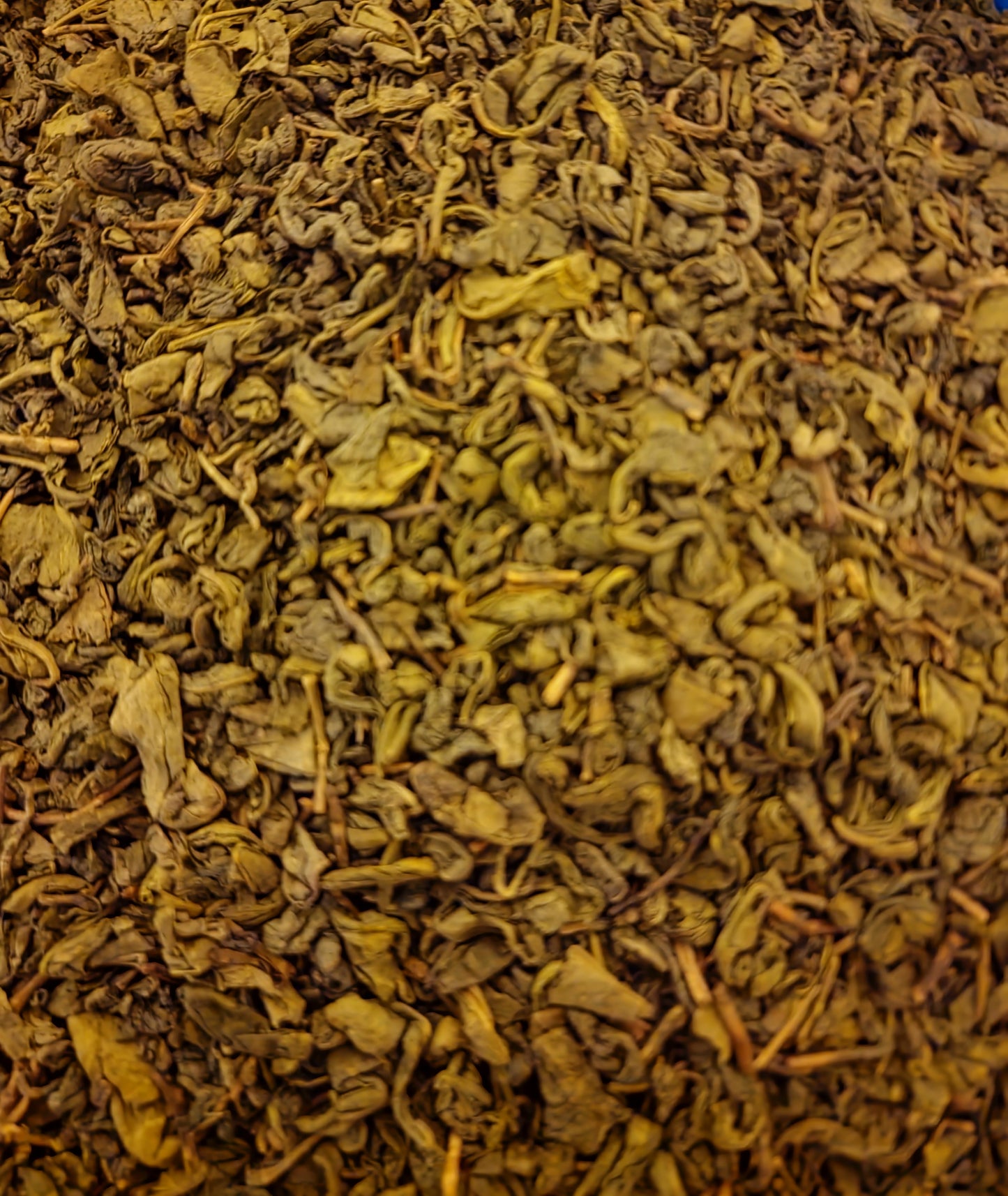 An overhead macro shot of loose Gunpowder Green Tea, showcasing the premium, tightly rolled grayish-green whole leaf pellets of authentic Camellia sinensis.