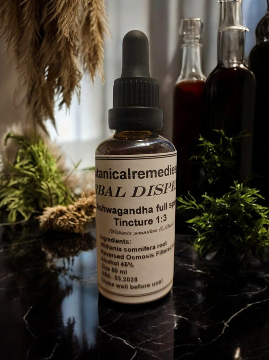 An amber glass dropper bottle of Botanical Remedies Ashwagandha Full Spectrum Tincture 1:3 resting on a dark marble apothecary counter, surrounded by dried botanicals and traditional herbal extraction bottles