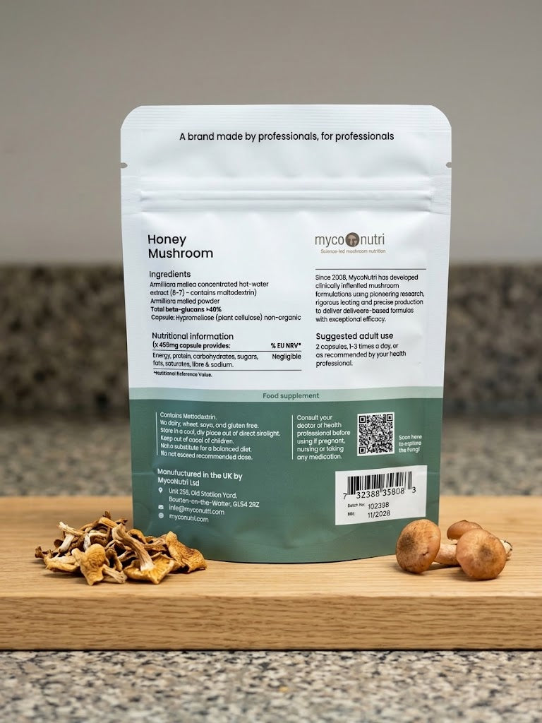 Back of the MycoNutri Organic Honey Mushroom pouch resting on a wooden board, displaying the concentrated Armillaria mellea extract ingredients, >40% beta-glucans specification, and organic certification.