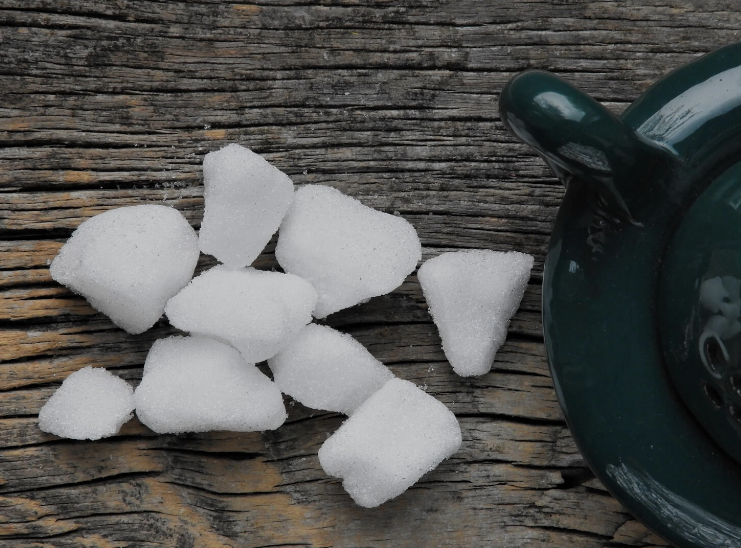 Pure white natural camphor lumps and crystals (Cinnamomum camphora) on a rustic wooden background next to an incense burner.