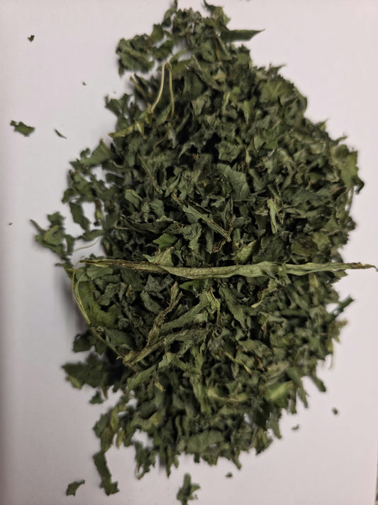 Dried organic and biodynamic comfrey leaf (Symphytum spp) cut pieces showing dark green curled leaves on a plain white background. Ideal for poultices and compresses.