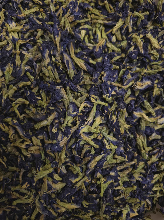 A close-up, highly detailed view of certified organic dried blue Butterfly Pea Flowers (Clitoria ternatea) sourced from Sri Lanka, showcasing their vibrant deep blue petals and pale green intact calyxes