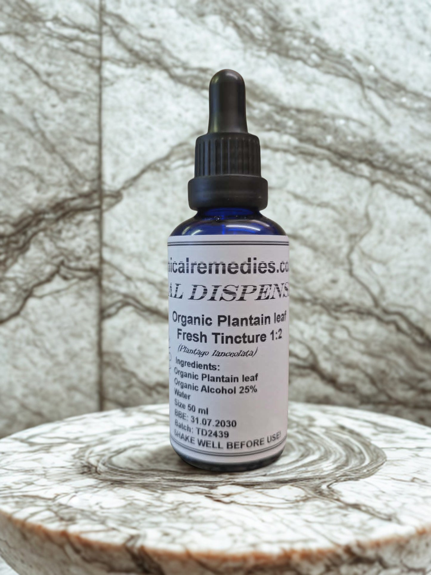 Organic Plantain Leaf Fresh Tincture (Plantago lanceolata) by Botanical Remedies. A 50ml blue glass dropper bottle displaying a practitioner-grade label with a 1:2 extraction ratio, resting on a beautifully textured marble surface