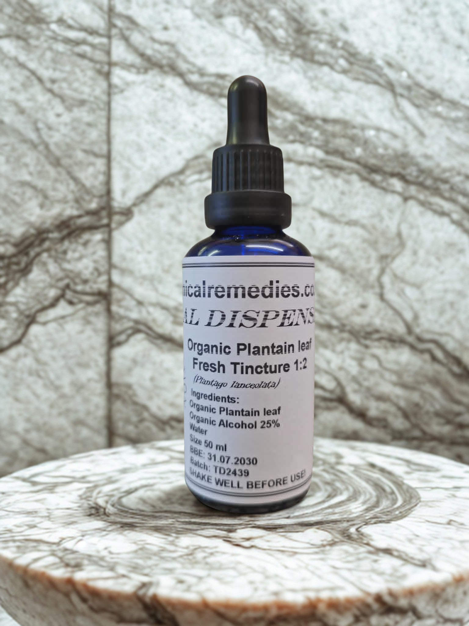 Organic Plantain Leaf Fresh Tincture (Plantago lanceolata) by Botanical Remedies. A 50ml blue glass dropper bottle displaying a practitioner-grade label with a 1:2 extraction ratio, resting on a beautifully textured marble surface