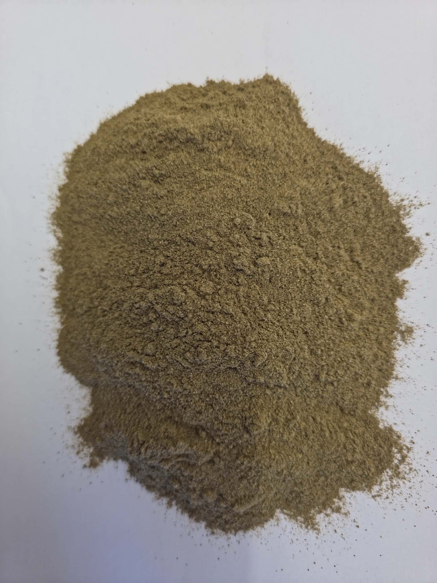 Pile of finely ground organic Trikatu powder featuring a blend of ginger, black pepper, and long pepper on a clean white background