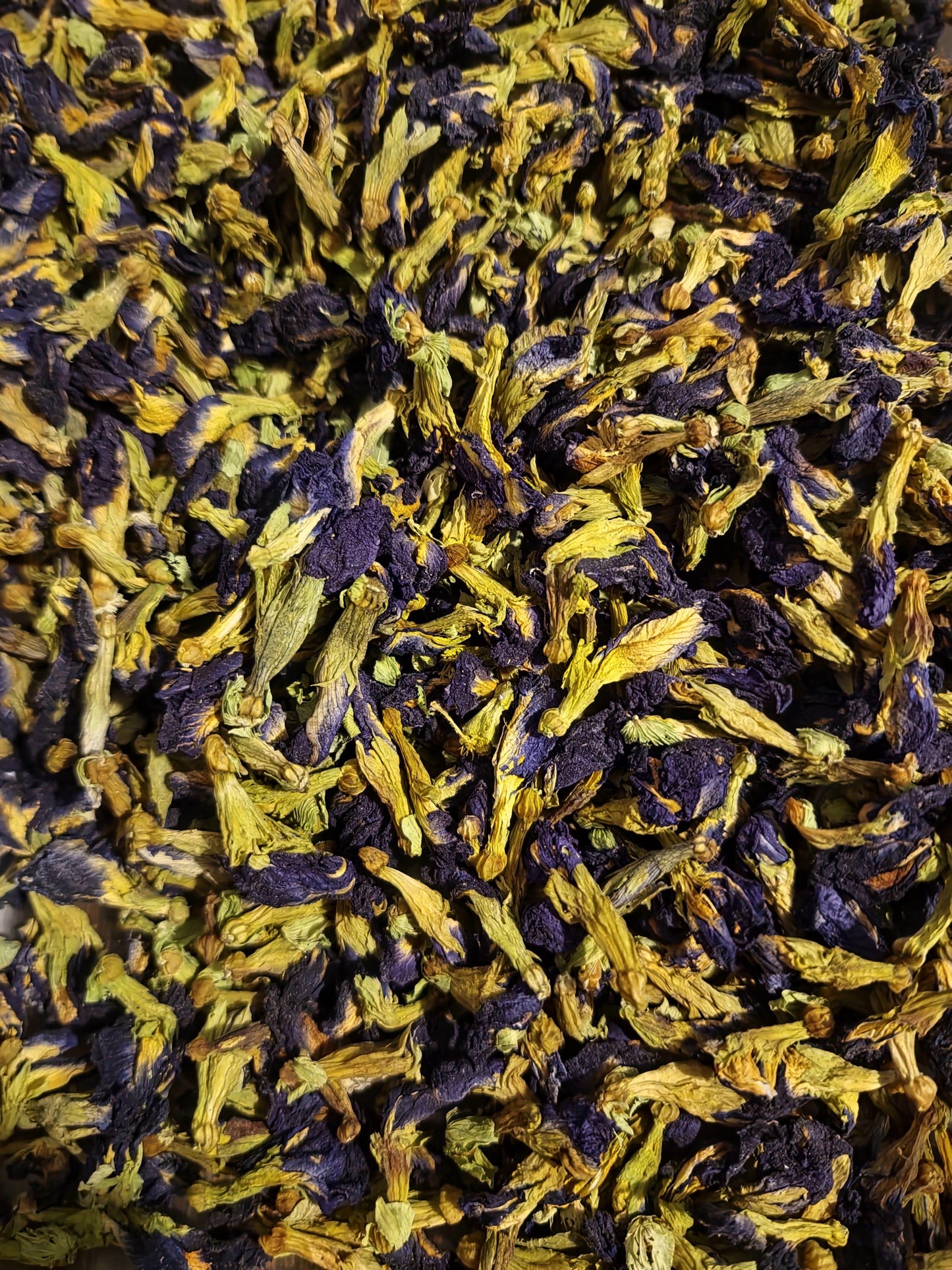 A close-up, highly detailed view of premium dried blue Butterfly Pea Flowers (Clitoria ternatea), showcasing their vibrant deep blue petals and pale green intact calyxes