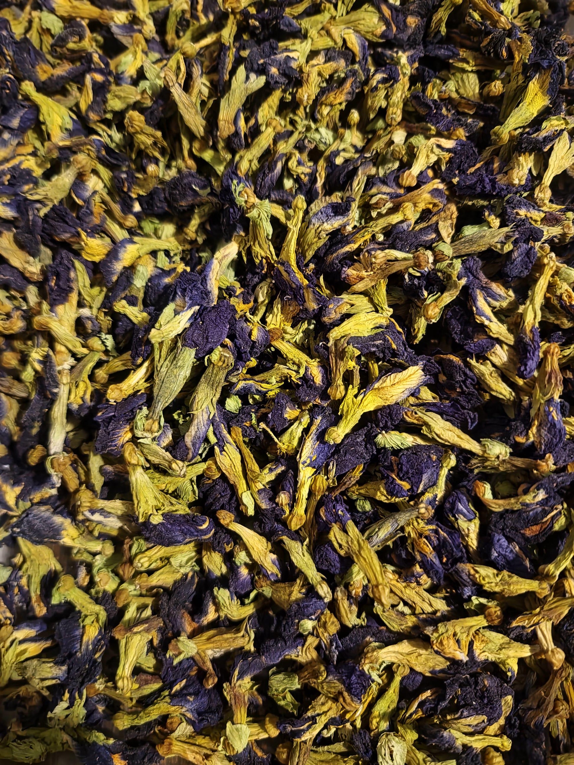 A close-up, highly detailed view of premium dried blue Butterfly Pea Flowers (Clitoria ternatea), showcasing their vibrant deep blue petals and pale green intact calyxes