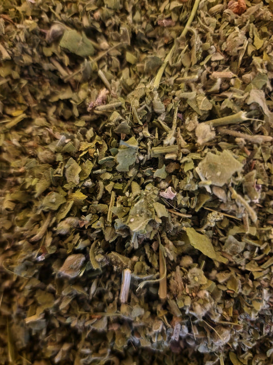An overhead macro photograph of loose Apothecary Grade dried and cut Marshmallow leaves, showcasing the velvety khaki-green texture and clean cut of wild-grown Polish Althaea officinalis.