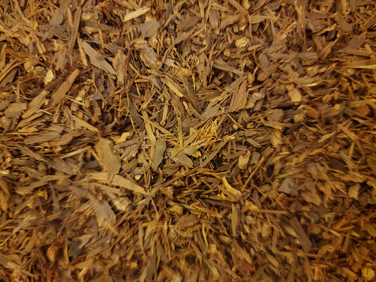 An overhead macro photograph of loose Apothecary Grade dried Pau D'Arco Bark, displaying the premium uniform mixture of earthy reddish-brown and dusty mahogany cut inner-bark shreds of sustainably wild-crafted South American Handroanthus impetiginosus.